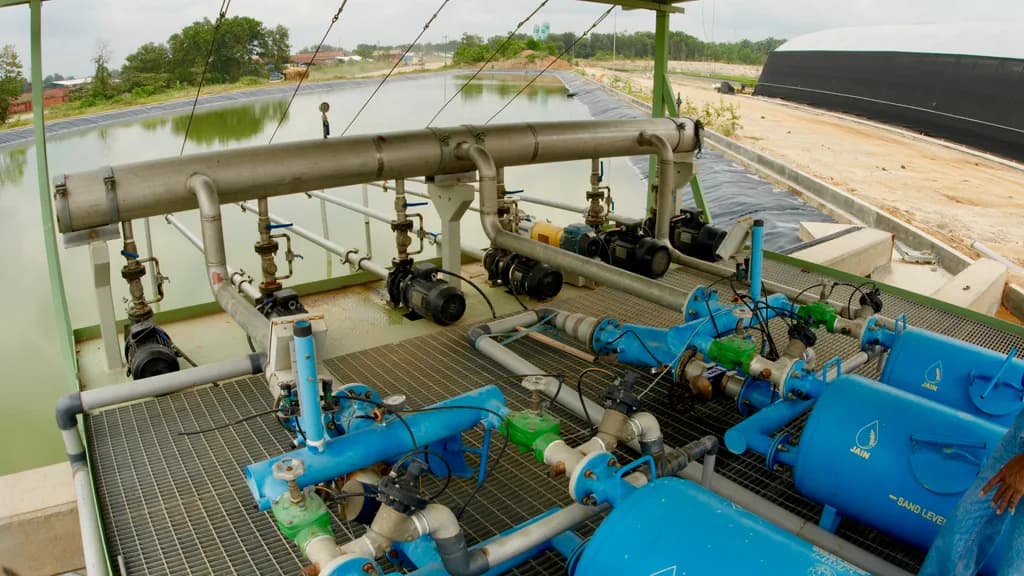 Pump and filtration station beside a large lined water reservoir.