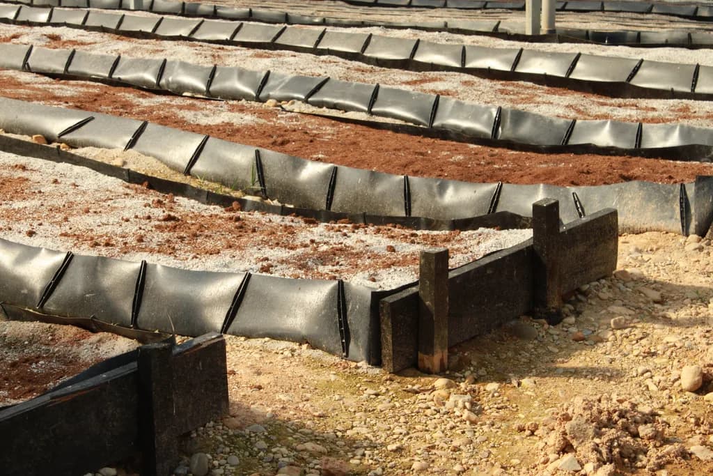 Detail of a raised bed's plastic-lined edges and corner posts, partially filled with growing media.